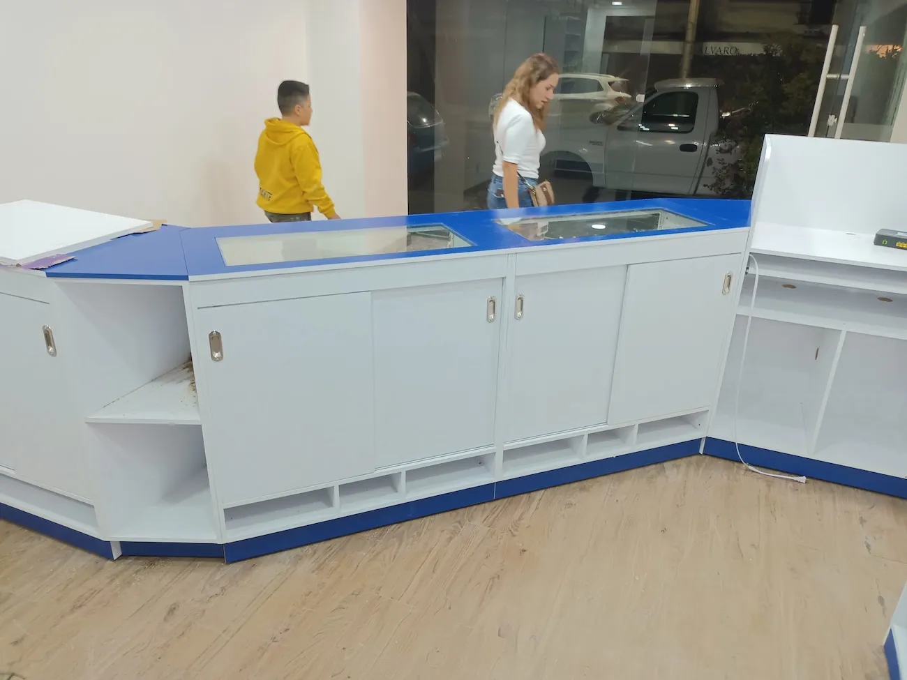 Mostrador curvo blanco con detalles azules y cubierta de cristal